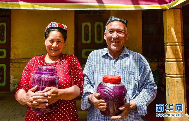 在和田市伊力其乡依盖尔其村，如则托合提·如孜（右）和爱人塔吉妮萨·伊敏在展示自己制作的玫瑰花酱（6月6日摄）。新华社记者 赵戈摄