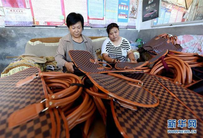 7月3日，临西县东倪庄村贫困户李兰玉（左一）和家人一起在家里加工箱包。