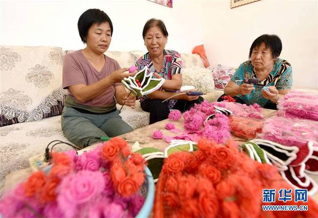 7月3日，临西县西马鸣堂村村民何秀华（左一）和村民一起加工手工粘花。