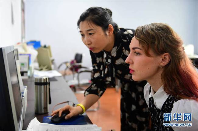 7月5日，克里斯蒂娜（右）在图们江日报社与同事合作进行报纸排版工作。