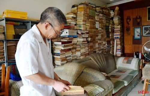  ↑刘国成在家中翻阅藏书，客厅“书墙”接近天花板