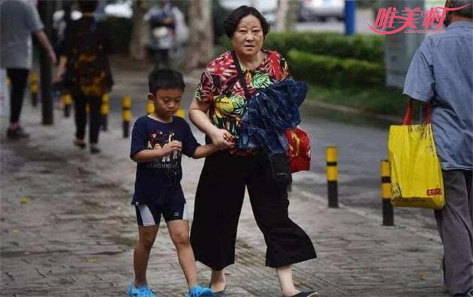 图为一位奶奶紧牵着孙子的手